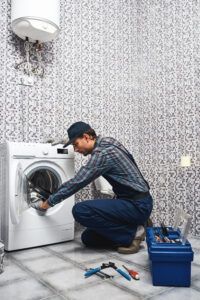 Appliance repairman works on washing machine