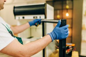 Appliance Repairman in uniform repairs refrigerator at home