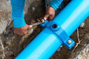 Man using a large wrench on water pipes.