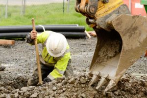 Construction worker digging dirt out with the help of crane