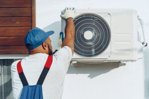 Repairman in uniform installing the outside unit of air conditioner