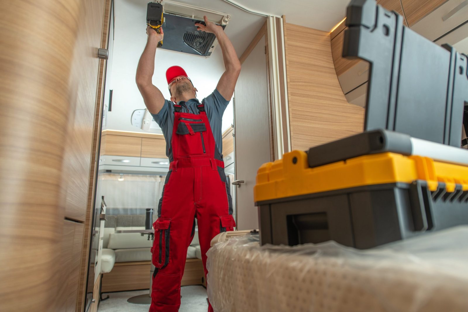 Appliance repairman repairing Travel Trailer Ceiling Mounted Air Condition Unit.